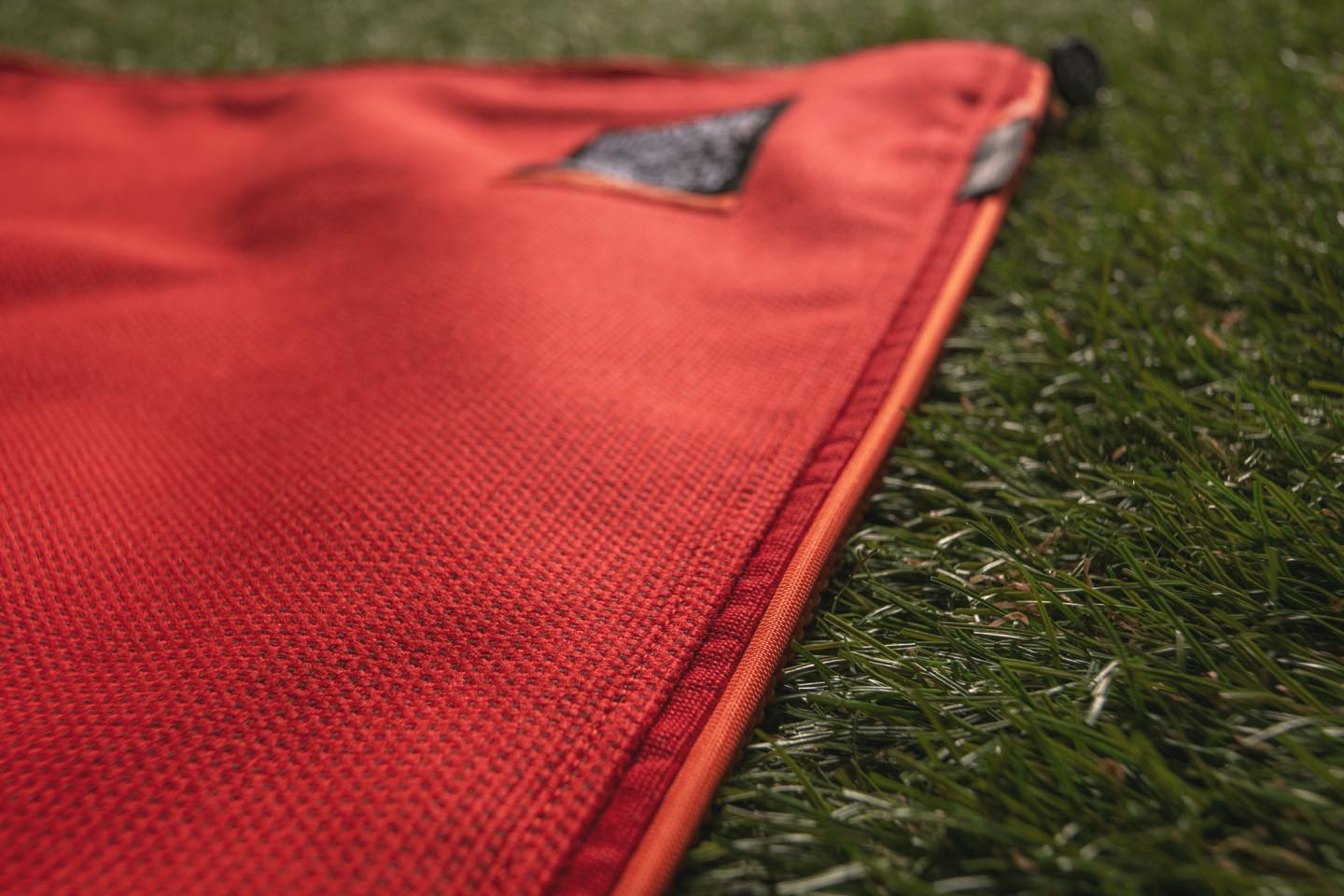 Close-up of the suba.squarepark.33.silvergrey showing premium craftsmanship, with a refined transition from the top fabric to the binding and orange piping