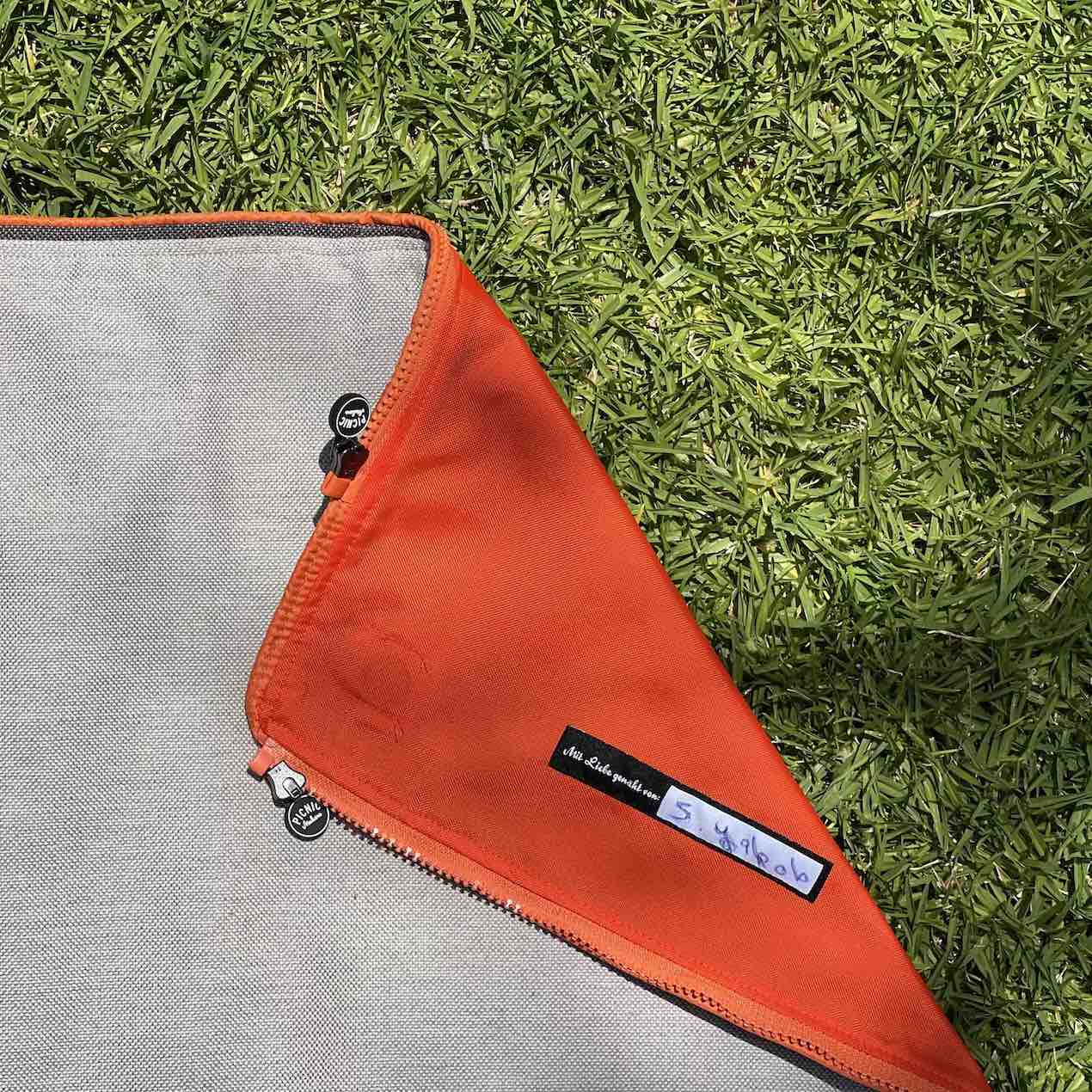A premium close-up of Fabric F1, revealing a bold orange underside with a refined folded finish