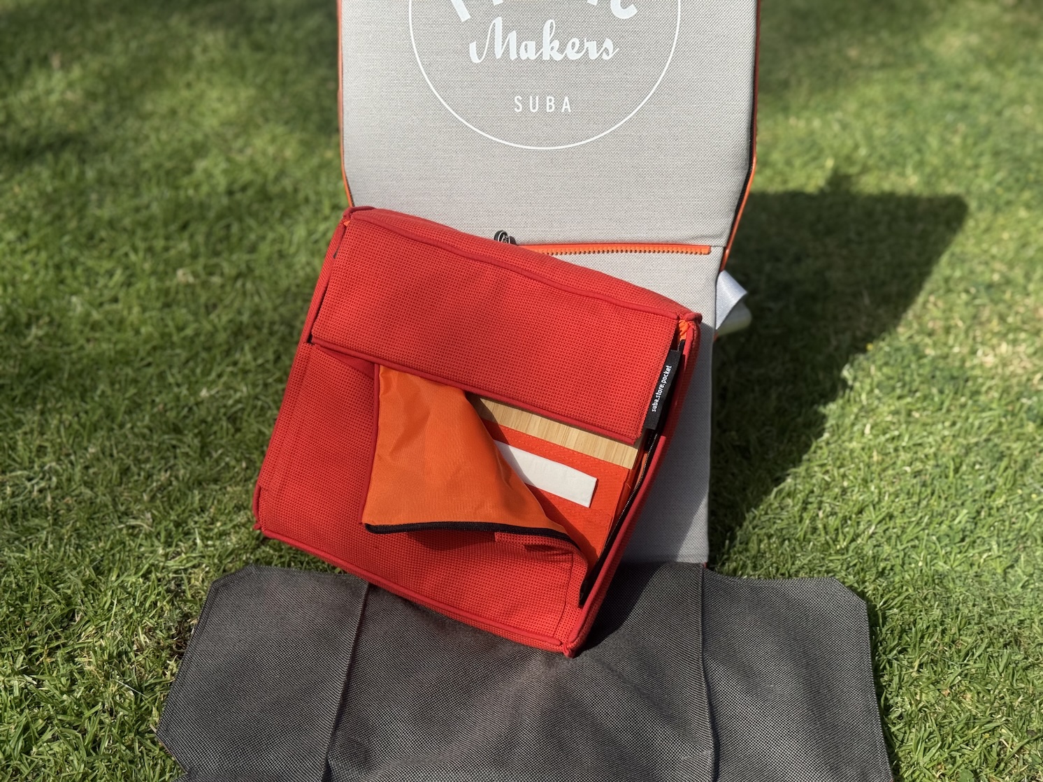 suba.backrest.silvergrey with attached suba.store.pocket via suba.zipSystem slightly open on grass sunlit outdoor setting ☀️🌿